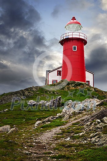 Red lighthouse on hill against stormy sky in Ferryland Newfoundland