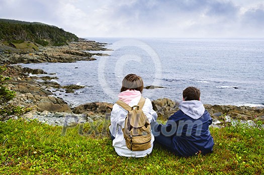 Children looking at coastal view of rocky Atlantic shore in Newfoundland, Canada