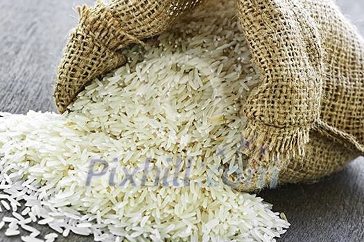 Raw long grain white rice grains in burlap bag Raw long grain white rice grains in burlap bag