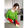 Girl cleaning kitchen with sponge and rubber gloves