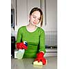 Girl cleaning kitchen with sponge and rubber gloves