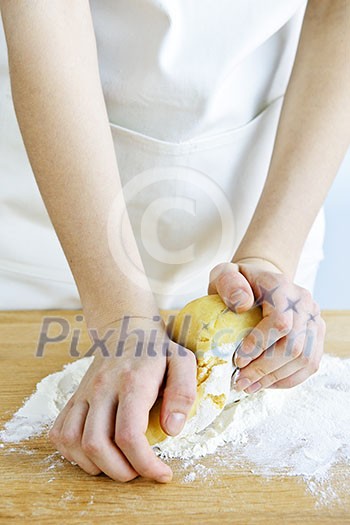Hands kneading ball of dough with flour on cutting board Hands kneading ball of dough with flour on cutting board