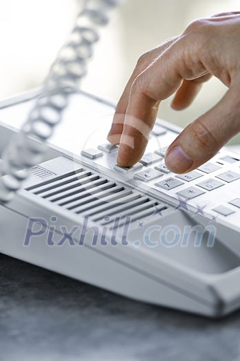 Close up of fingers dialing a desktop telephone