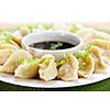 Closeup on plate of steamed dumplings with soy sauce