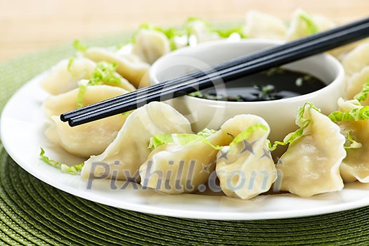 Closeup on plate of steamed dumplings with soy sauce and chopsticks Closeup on plate of steamed dumplings with soy sauce and chopsticks