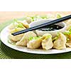 Closeup on plate of steamed dumplings with soy sauce and chopsticks
