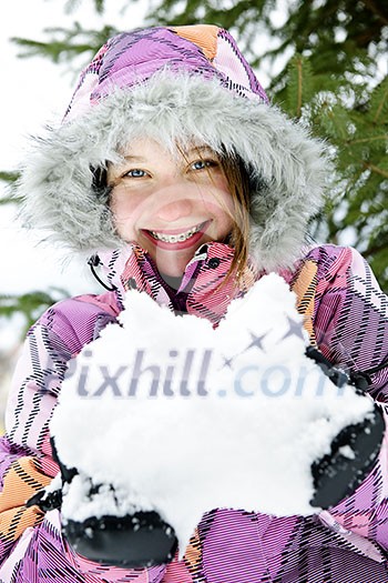 Portrait of happy teenage girl holding snow in gloves