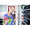 Pretty, young woman taking fresh vegetables from her fridge - being on a gluten free vegan diet does not seem to be a problem for her (shallow DOF; color toned image)