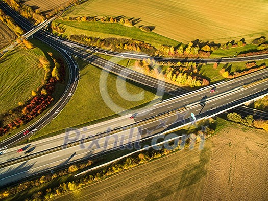 Aerial view of a highway amid fields with cars on it Aerial view of a highway amid fields with cars on it
