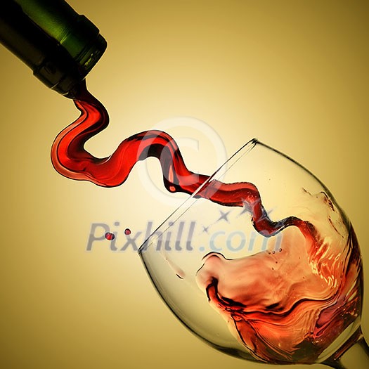Pouring red wine in goblet on yellow background