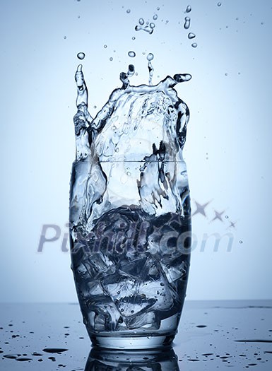 Water splash in glass with ice cubes.