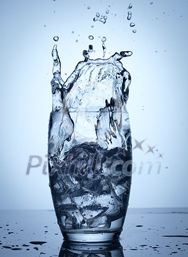 Water splash in glass with ice cubes. Water splash in glass with ice cubes.