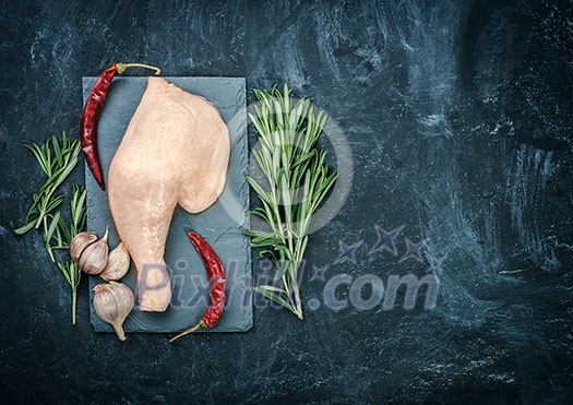 Raw chicken thigh on black stone plate with herbs. Copyspace. Raw chicken thigh on black stone plate with herbs. Copyspace.