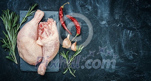 Raw chicken thigh on black stone plate with herbs Raw chicken thigh on black stone plate with herbs