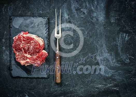 Raw beef steak on the stone plate over black table. Copyspace. Raw beef steak on the stone plate over black table. Copyspace.