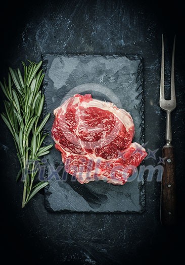 Raw beef steak with rosemary on stone plate Raw beef steak with rosemary on stone plate