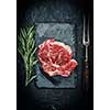 Raw beef steak with rosemary on stone plate