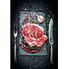 Raw meat steak entrecote on the stone plate with spice on the dark table
