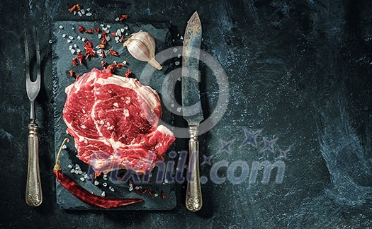 Raw beef steak with salt and herbs on the stone plate