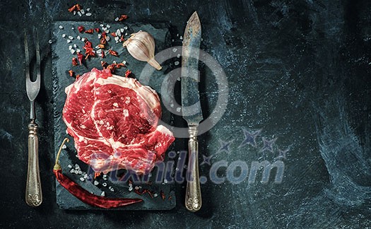 Raw beef steak with salt and herbs on the stone plate Raw beef steak with salt and herbs on the stone plate