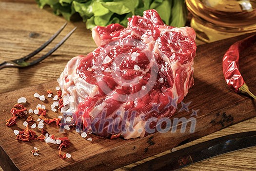 Raw beef steak with salt and herbs on wooden cutting board