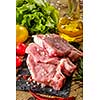 Raw pork steaks on stone board with herbs, tomatoes and lemon