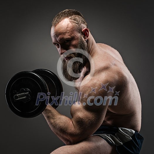 Muscular bearded bodybuilder guy doing exercises with dumbbells