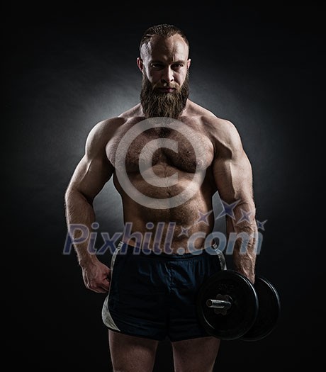 Strong bodybuilder with six pack, perfect abs, shoulders, biceps, triceps and chest. Power athletic bearded man in training pumping up muscles with dumbbell. Strong bodybuilder with six pack, perfect abs, shoulders, biceps, triceps and chest. Power athletic bearded man in training pumping up muscles with dumbbell.