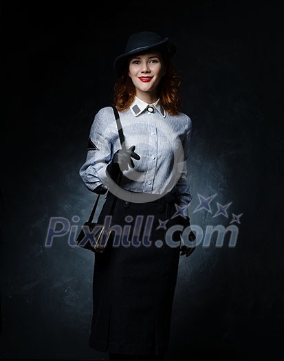 Red-haired girl in retro dress on a dark background. A long skirt and a dark hat. Keeps bag on his shoulder. Red-haired girl in retro dress on a dark background. A long skirt and a dark hat. Keeps bag on his shoulder.