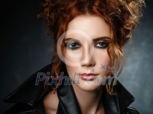 Portrait of red-haired woman in a leather jacket on a dark background. Seductive look at the camera. Portrait of red-haired woman in a leather jacket on a dark background. Seductive look at the camera.
