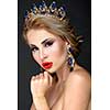 Beautiful blonde girl with a golden crown, earrings and professional evening make-up. Beauty face.