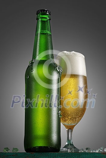 Bottle and glass of beer on the wooden table over grey background Bottle and glass of beer on the wooden table over grey background