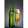 Bottle and glass of beer on the wooden table over grey background