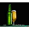 Bottle and glass of beer on the wooden table over black background