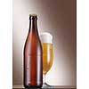 Cold Bottle and glass of beer on the table over beige background