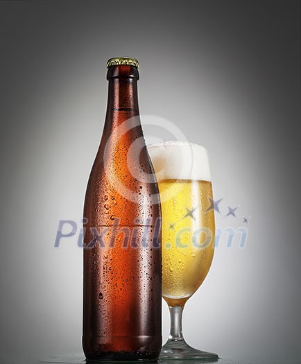 Bottle and glass of beer on the wooden table over grey background Bottle and glass of beer on the wooden table over grey background
