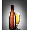 Bottle and glass of beer on the wooden table over grey background