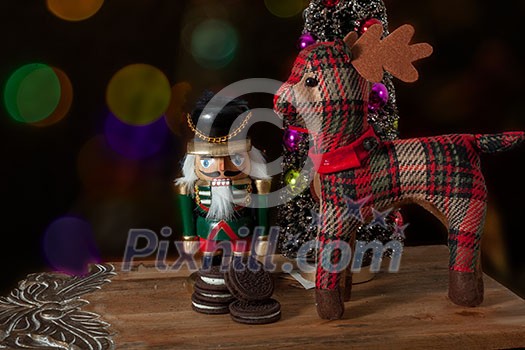 Toy figure wooden nutcracker statue and santas deer Roudolph standing in front of decorated Christmas lights, vintage style