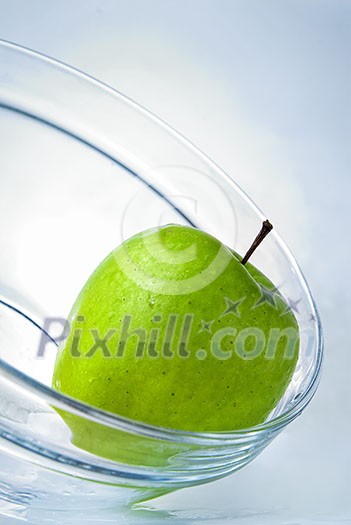 green apple in glass plate on blue background