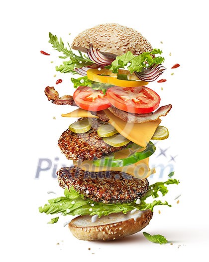 Delicious monster burger with flying ingredients isolated on white background Delicious monster burger with flying ingredients isolated on white background