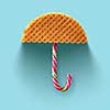 Umbrella made of waffle and Christmas candy on a blue background.