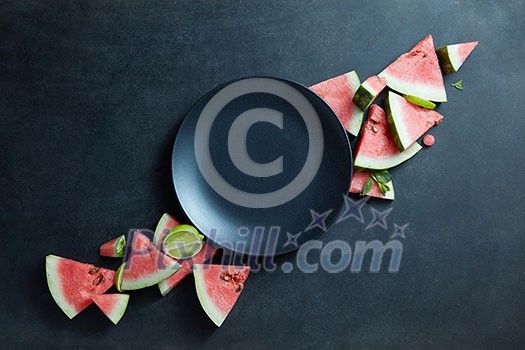 black plate and slices of fresh watermelon on a black background