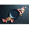 black plate and slices of fresh watermelon on a black background