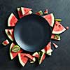 slices of watermelon placed in a circle of black plate. Space for text