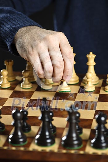 Hand moving a pawn chess piece on wooden chessboard as first move Hand moving a pawn chess piece on wooden chessboard as first move