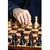 Hand moving a pawn chess piece on wooden chessboard as first move