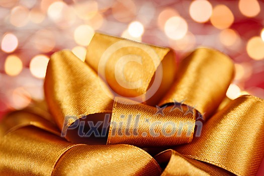Golden ribbon gift bow closeup with festive lights Golden ribbon gift bow closeup with festive lights