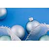 Glass Christmas balls with holiday ribbon on blue background