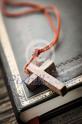 Closeup of simple wooden Christian cross necklace on holy Bible Closeup of simple wooden Christian cross necklace on holy Bible