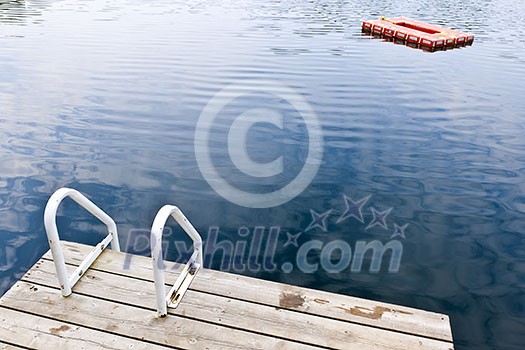 Dock and ladder on calm summer lake with diving platform in Ontario Canada
